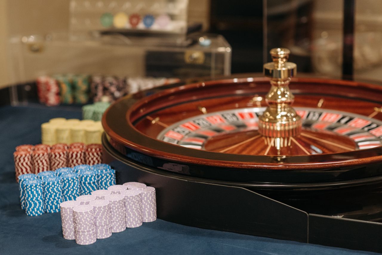 Mahogany roulette wheel with colourful chip stacks on navy felt