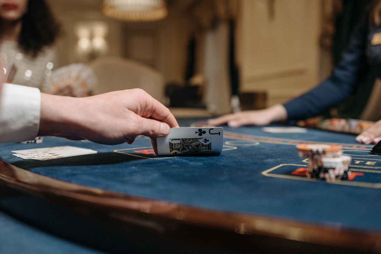 Player revealing the jack of clubs at a blue gaming table
