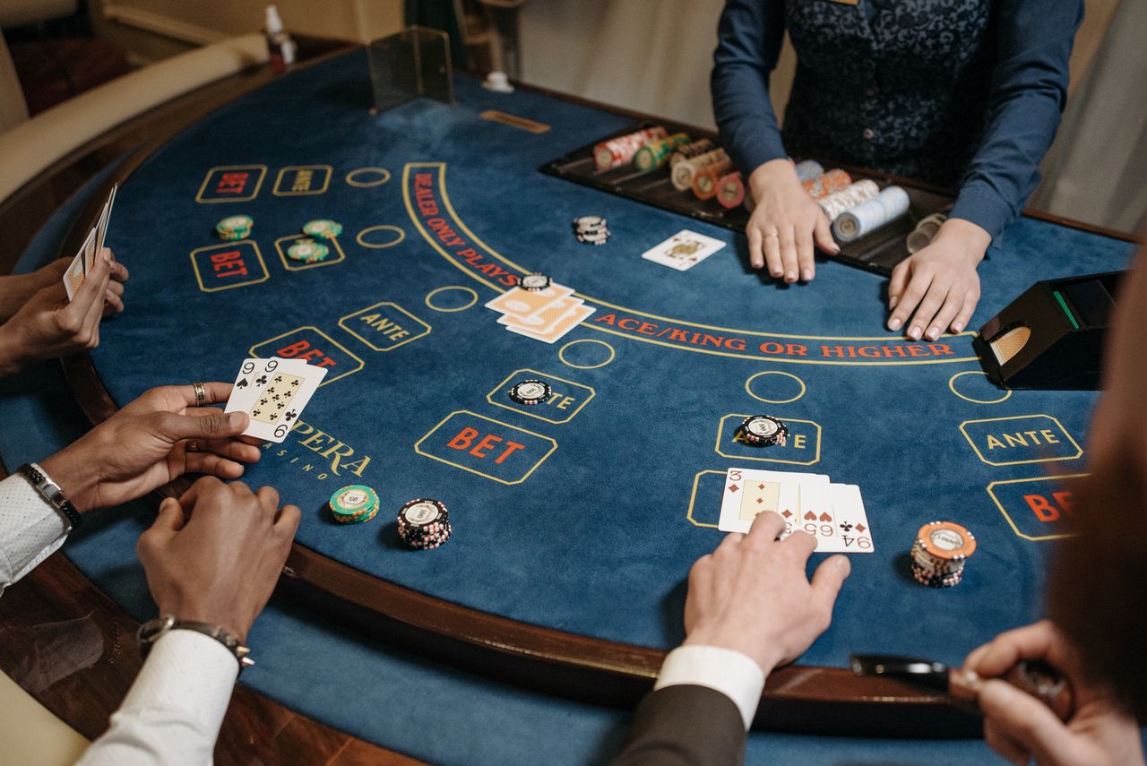 Card table with dealer tray and players seated around blue felt